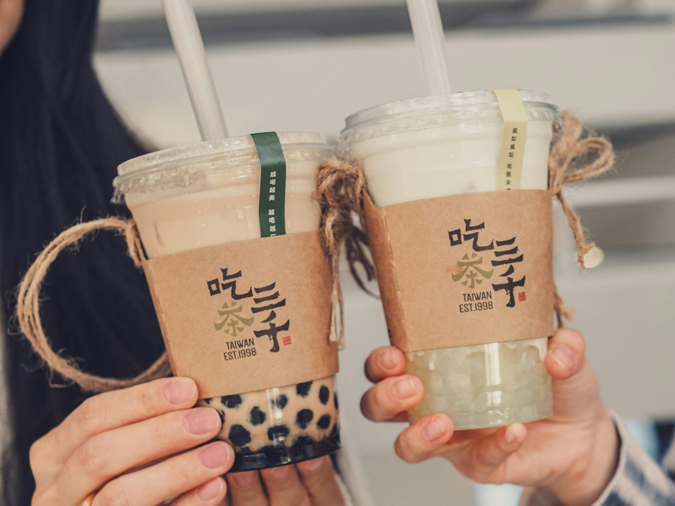 Two people holding bubble tea cups together, showcasing different flavors in plastic cups.